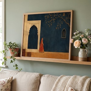 May include: A framed rectangular wall art print featuring a dark blue background with a person in a vibrant orange garment walking past a light-coloured stone archway. A golden tree branch extends from the top right corner near a small window.