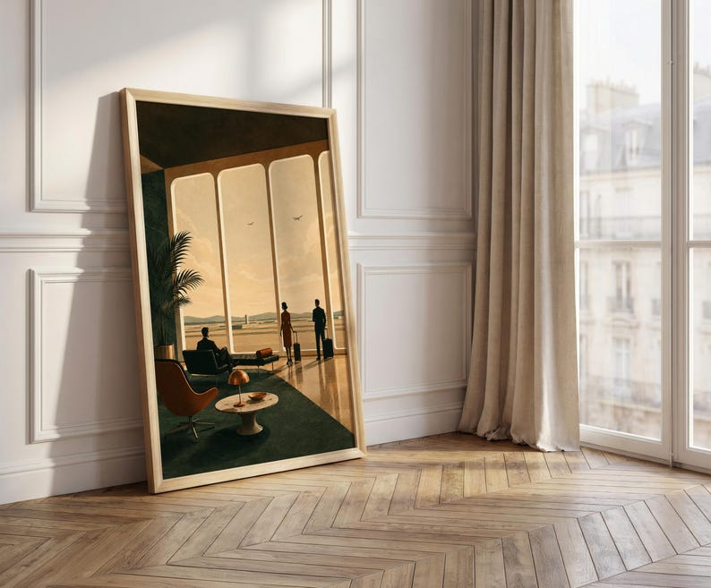 May include: A framed rectangular wall art print depicting an airport lounge scene with large windows, a dark green carpet, a brown lounge chair, a small round table with a lamp, and three figures standing or sitting with luggage in a warm light.