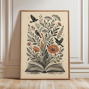 Può includere: Una stampa artistica incorniciata raffigurante un libro aperto con illustrazioni a inchiostro nero di vari fiori selvatici, steli frondosi e tre uccelli in volo o appollaiati. La tavolozza dei colori include arancione tenue, verde salvia e nero.