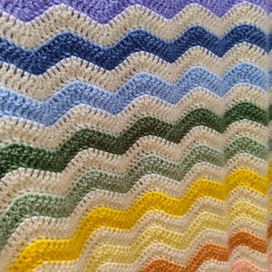 May include: A colorful crocheted blanket with a chevron pattern in shades of purple, blue, green, yellow, and orange.