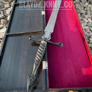 May include: A black and silver sword with a detailed handle and a black wooden box with a red velvet lining. The box has the text "BLAYDZ_KNIFE_CO" on the front.