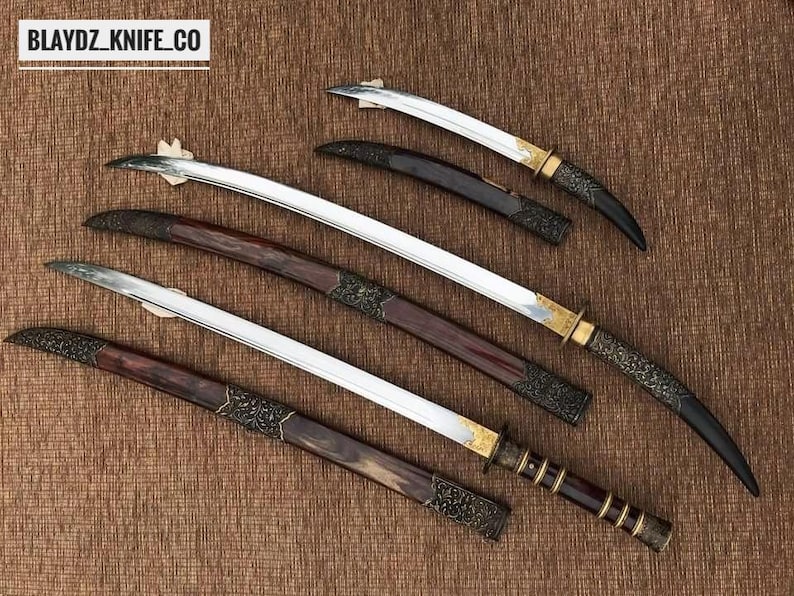 May include: Overhead view of several swords with curved blades and decorative handles. The blades are silver, and the handles feature dark wood, gold accents, and ornate metalwork. The text "BLAYDZ_KNIFE_CO" is visible in the top left corner.