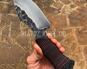 May include: A handcrafted knife with a curved, silver blade and a textured edge. The handle is wrapped in dark red cord. The text "BLAYDZ KNIFE CO" is visible on the blade.