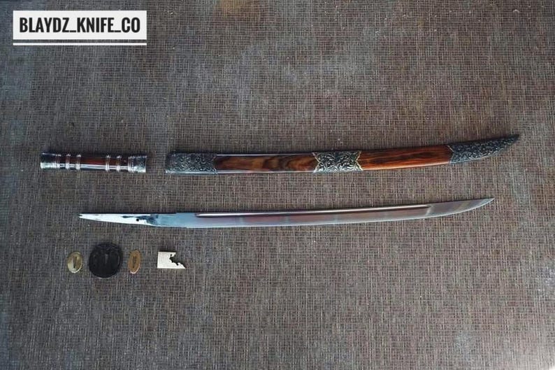 May include: A disassembled sword with a wooden handle and silver detailing. The blade is silver, and the scabbard is brown with silver accents. The text "BLAYDZ_KNIFE_CO" is in a white box in the upper left corner.