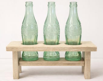Jarrón vintage de Coca-Cola con tres cogollos y botellas: soporte rústico de madera hecho a mano, centro de mesa rústico.