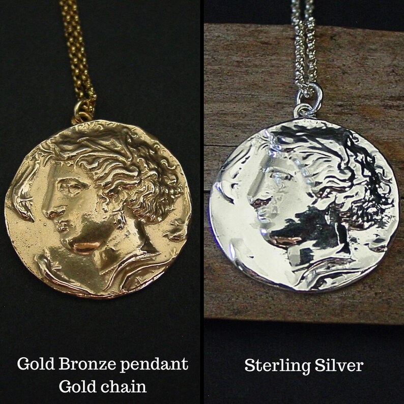 May include: Two versions of a round pendant necklace featuring a profile of a woman's face. The pendant on the left is gold bronze with a gold chain. The pendant on the right is sterling silver with a silver chain.  Gold Bronze pendant, Gold chain, Sterling Silver.