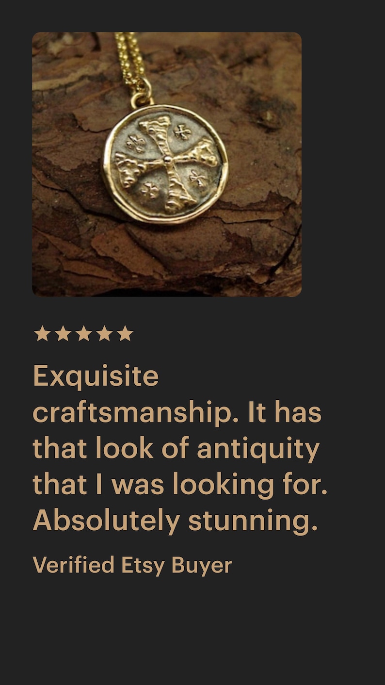 May include: A gold-toned circular pendant necklace featuring a raised cross design with textured, weathered detailing on the surface. The pendant is suspended from a delicate gold-toned chain, showcasing a metallic finish with a worn, aged appearance.