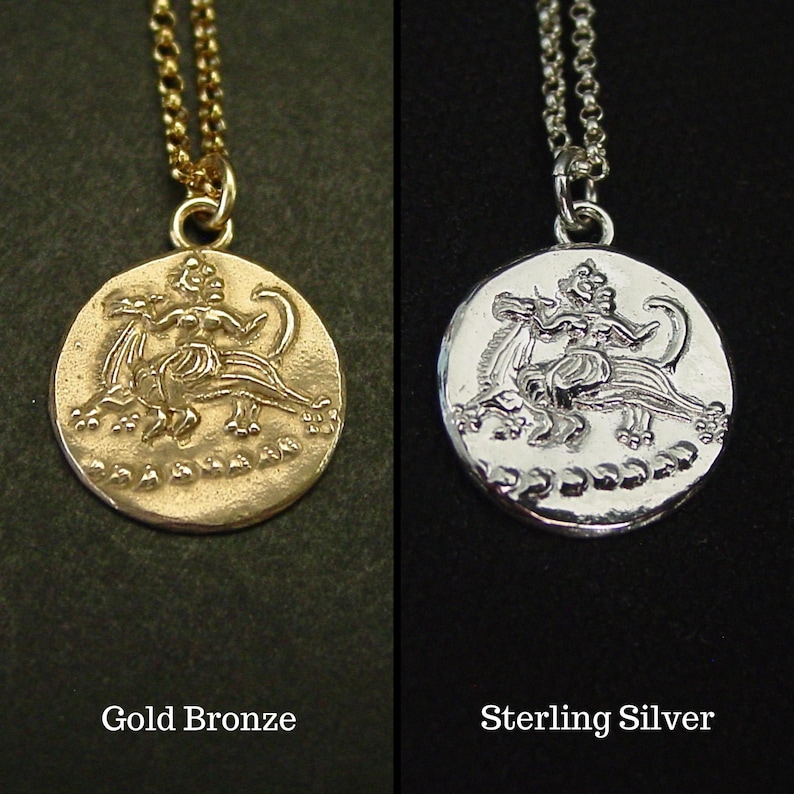 May include: A gold bronze pendant necklace and a sterling silver pendant necklace, both featuring a circular coin design with a relief of a figure riding a mythical creature. Each pendant hangs from a matching metal chain, with text labels.