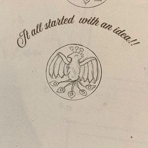 May include: A sketch of a bird with outstretched wings inside a circle. The bird has a crown and peacock-like tail feathers. The text "It all started with an idea!!" is written above the circle in cursive.