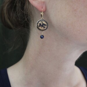 May include: Gold tone earrings with a black enamel eagle design and a dangling black bead.