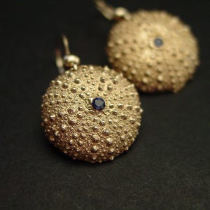 Brincos delicados de ouriço-do-mar em safira azul: joias artesanais inspiradas no oceano, feitas com conchas para amantes da praia.