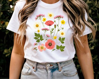 May include: White t-shirt with a floral print featuring pink and red flowers, green leaves, and yellow centers.
