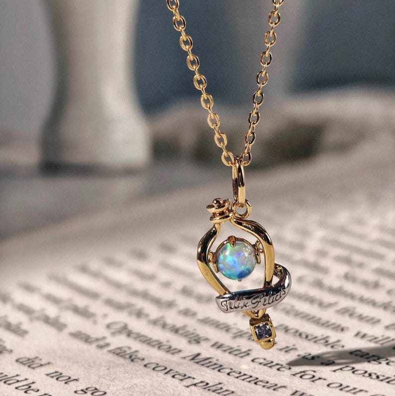 Detailed close up of the Felix Felicis potion bottle pendant, highlighting the quality of the opal and gold finish on a vintage paper background.