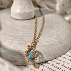 Angled view of the magical Felix Felicis opal necklace resting on a textured, off-white fabric to showcase its craftsmanship and vintage charm.