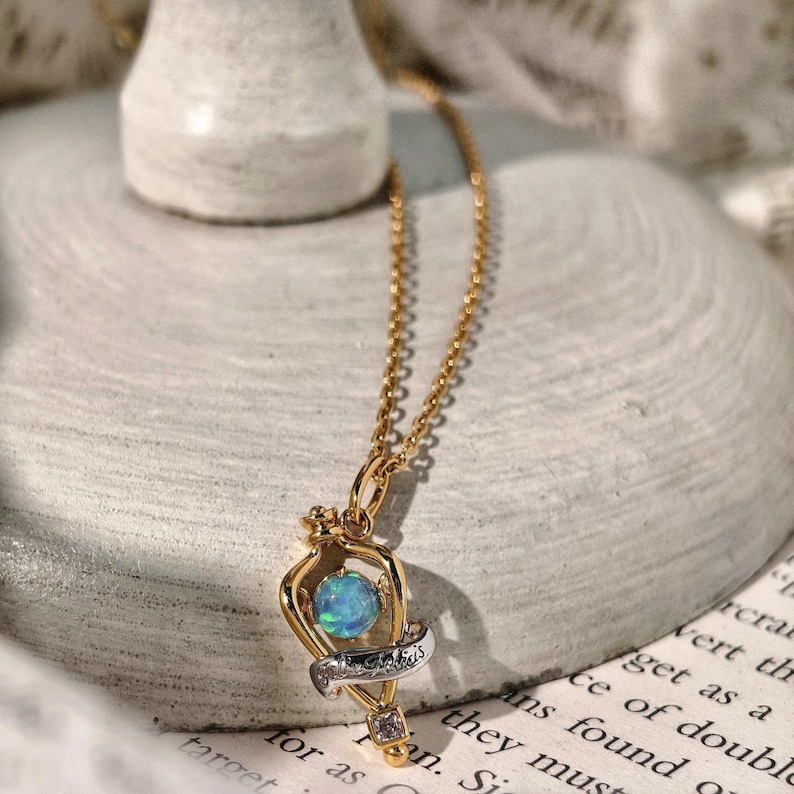 Angled view of the magical Felix Felicis opal necklace resting on a textured, off-white fabric to showcase its craftsmanship and vintage charm.