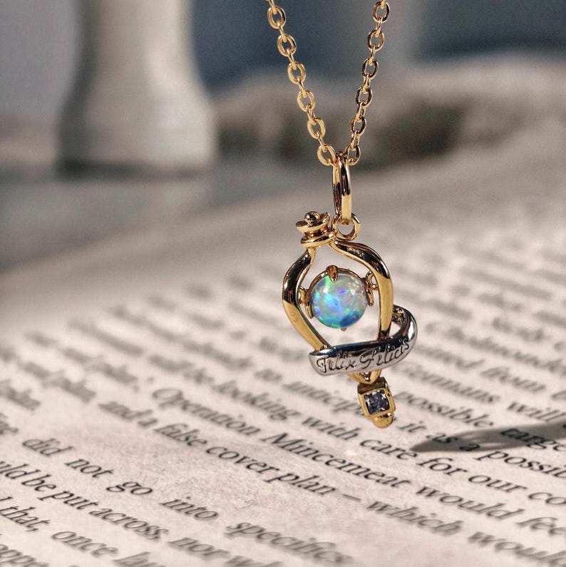 Detailed close up of the Felix Felicis potion bottle pendant, highlighting the quality of the opal and gold finish on a vintage paper background.