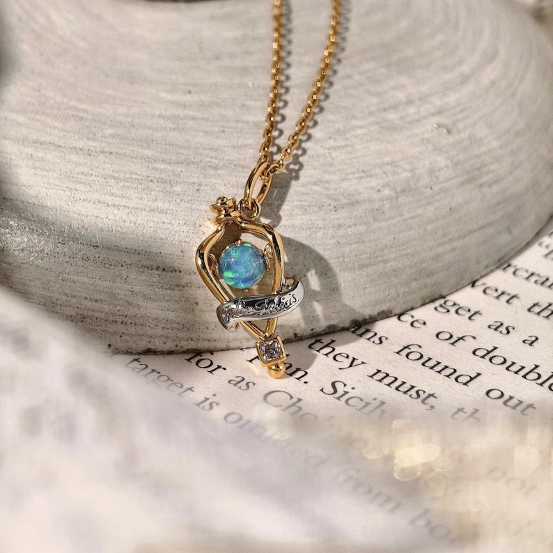Angled view of the magical Felix Felicis opal necklace resting on a textured, off-white fabric to showcase its craftsmanship and vintage charm.
