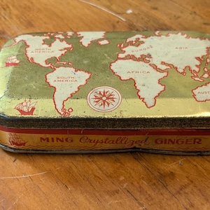 May include: A vintage tin box with a world map design and the text "Ming Crystallized Ginger". The box is gold with red and white accents.