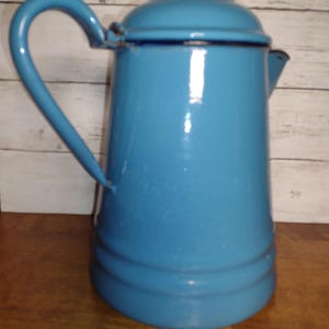 May include: A blue enamel coffee pot with a lid and a handle. The pot has a slightly rounded shape and a smooth surface.