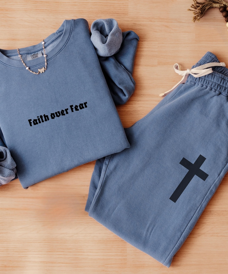 May include: A blue sweatshirt with the text "Faith over Fear" and a pair of matching blue sweatpants with a black cross graphic.