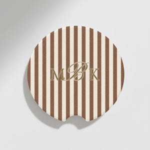 May include: Round car coaster with a brown and cream vertical striped pattern. The coaster features the gold-colored initials "MBK" in an elegant script font. The coaster has a small notch for easy removal from a car cup holder.
