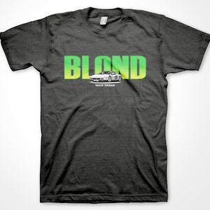 May include: A dark gray t-shirt with a green and yellow gradient graphic that says "BLOND" with a white Ferrari car underneath. The text "WHITE FERRARI" is below the car.