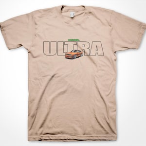 May include: A tan t-shirt with the word "ULTRA" printed in black letters. The word "nostalgia" is printed in green letters above the word "ULTRA". A cartoon image of a red and orange car is printed in the center of the word "ULTRA".