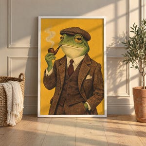 May include: A framed wall art print featuring an anthropomorphic green frog wearing a brown tweed suit, a white collared shirt, a dark tie, and a flat cap. The frog is holding a smoking tobacco pipe against a solid yellow background.