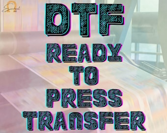 May include: Image featuring the text "DTF READY TO PRESS TRANSFER" in a bold, black font with a teal and pink outline. The text is layered over a blurred background of printing machinery and soft pastel colors.