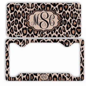 May include: A license plate and frame set featuring a leopard print design in shades of brown and tan. The license plate has a central monogram in a decorative frame. The frame also has the leopard print pattern.