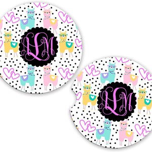 May include: Two car coasters with a white background, black polka dots, and a pattern of colorful llamas wearing glasses and hearts. A black circle in the center features the letters "LM" in pink.
