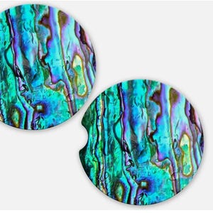May include: Two round car coasters with a vibrant, iridescent abalone shell design. The coasters feature a mix of teal, blue, purple, and green hues, creating a unique and eye-catching pattern. Each coaster has a small notch for easy removal from a car cup holder.