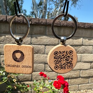 May include: Two wooden keychains with silver key rings. One keychain is square and has the text "CIRCLEPLEX DESIGN" and a circular logo. The other keychain is round and has a black and white QR code.