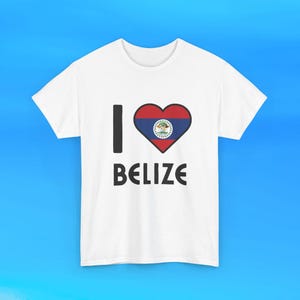 Pode incluir: Uma t-shirt branca de manga curta com a letra I preta, um gráfico em forma de coração contendo a bandeira vermelha, branca e azul do Belize, e a palavra BELIZE impressa em letras maiúsculas pretas abaixo do coração na frente.