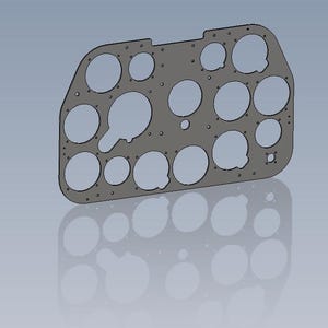 May include: A gray metal panel with multiple circular cutouts of varying sizes, designed for mounting instruments. Small holes are evenly spaced around the cutouts. The panel has a curved edge on one side and a reflective surface below.