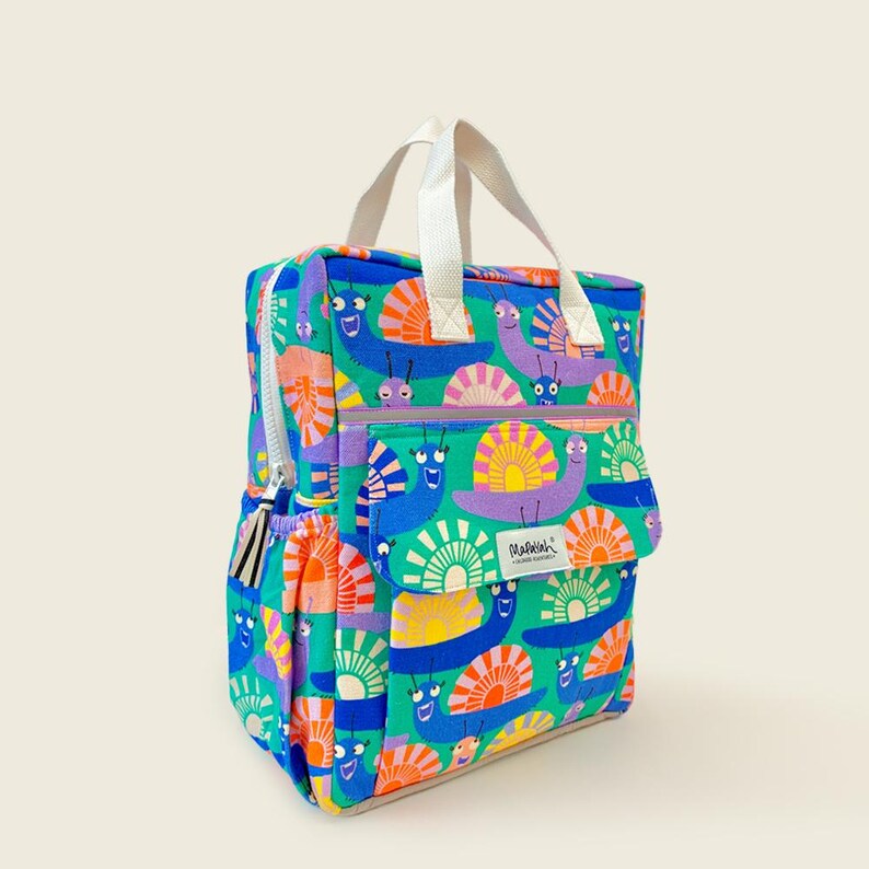 Colorful kids backpack with cheerful snail print on a bright blue background, featuring a front pocket, side pouch, and white handles - fun and durable for everyday use.