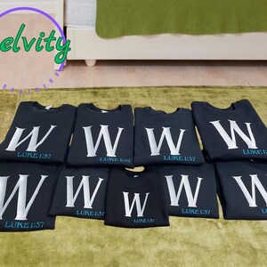 May include: Eight black t-shirts with a white letter W and the text "LUKE 1:37" in blue.