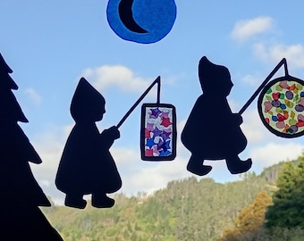May include: Silhouette cutouts of figures carrying lanterns and walking between stylized evergreen trees. A crescent moon is in the sky. The lanterns have colorful designs, including stars, confetti, and autumn leaves. The background is a view of a mountain range.