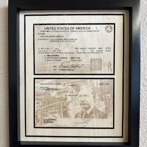 Può includere: Documento incorniciato degli Stati Uniti d'America, con testo e un ritratto. Il documento include dettagli come nome, indirizzo e informazioni sul certificato. La cornice è nera.