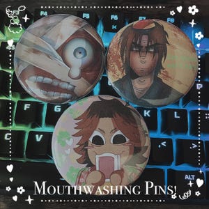 Peut inclure: Trois épingles rondes avec des motifs colorés. La première épingle représente un visage de dessin animé avec un bandage sur l'œil. La deuxième épingle représente un visage de dessin animé avec un bandage sur l'œil. La troisième épingle représente un visage de dessin animé avec un bandage sur l'œil. Les épingles sont sur un clavier.