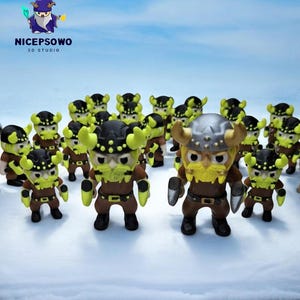 May include: A collection of small Viking figurines with black helmets, yellow horns, and brown bodies. The figurines have yellow beards and are standing on a snowy surface. The image includes the text "NICEPSOWO 3D STUDIO" in the upper left corner.
