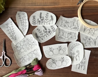 May include: A set of 11 embroidery patterns featuring various floral designs on white fabric. The patterns include flowers, leaves, and stems, and are perfect for beginners or experienced embroiderers.