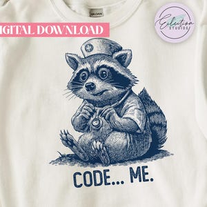 May include: White sweatshirt featuring a blue illustration of a raccoon dressed as a nurse, holding a stethoscope. The text "CODE... ME." is printed below the raccoon. The words "DIGITAL DOWNLOAD" are in a pink banner at the top.