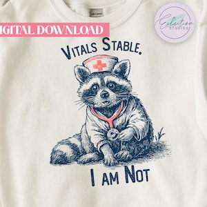 May include: White sweatshirt with a graphic of a raccoon dressed as a nurse, wearing a stethoscope and a nurse's cap. Text reads "Vitals Stable, I AM Not". The words "Digital Download" are at the top.