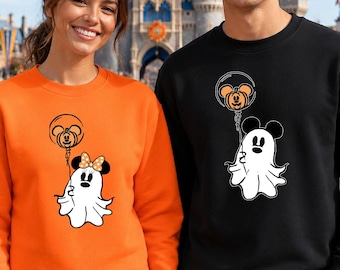 May include: An orange sweatshirt featuring a white ghost with a Minnie Mouse bow holding a pumpkin balloon, and a black sweatshirt featuring a white ghost holding a pumpkin balloon, both with Mickey Mouse ears on the ghost and balloon designs.