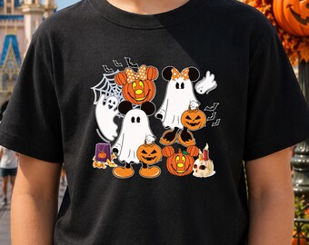 May include: A black t-shirt featuring a graphic print of two cartoon characters dressed as ghosts, surrounded by orange jack-o'-lanterns, a spider web, small bats, a purple treat bag, and a skull candle, all arranged in a festive Halloween design.