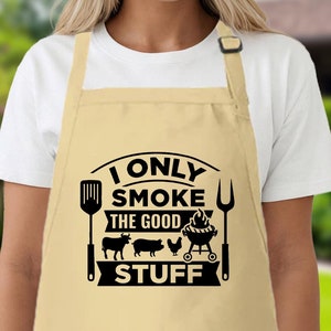 May include: A beige apron with a black graphic that says "I only smoke the good stuff" with a grill, spatula, fork, cow, pig, and chicken.