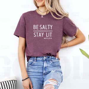 May include: A maroon t-shirt with the text "BE SALTY STAY LIT" and the scripture reference "MATT 5:13-14" in white.
