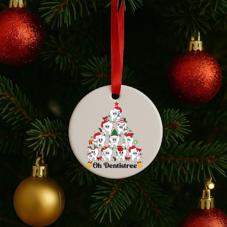 Puede incluir: Adorno navide&ntilde;o redondo y blanco con una cinta roja. El adorno presenta un dise&ntilde;o de &aacute;rbol de Navidad hecho de dientes de dibujos animados con gorros de Pap&aacute; Noel. El texto "Oh Dentistree" est&aacute; en la parte inferior del adorno.