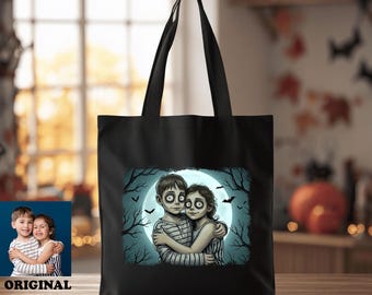 May include: A black tote bag featuring a graphic illustration of two children with large eyes embracing in front of a bright full moon, surrounded by dark tree silhouettes and small bats, with two long shoulder straps for carrying items.